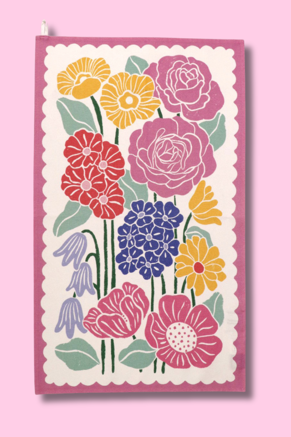 A cotton kitchen towel with a floral print against a light pink background