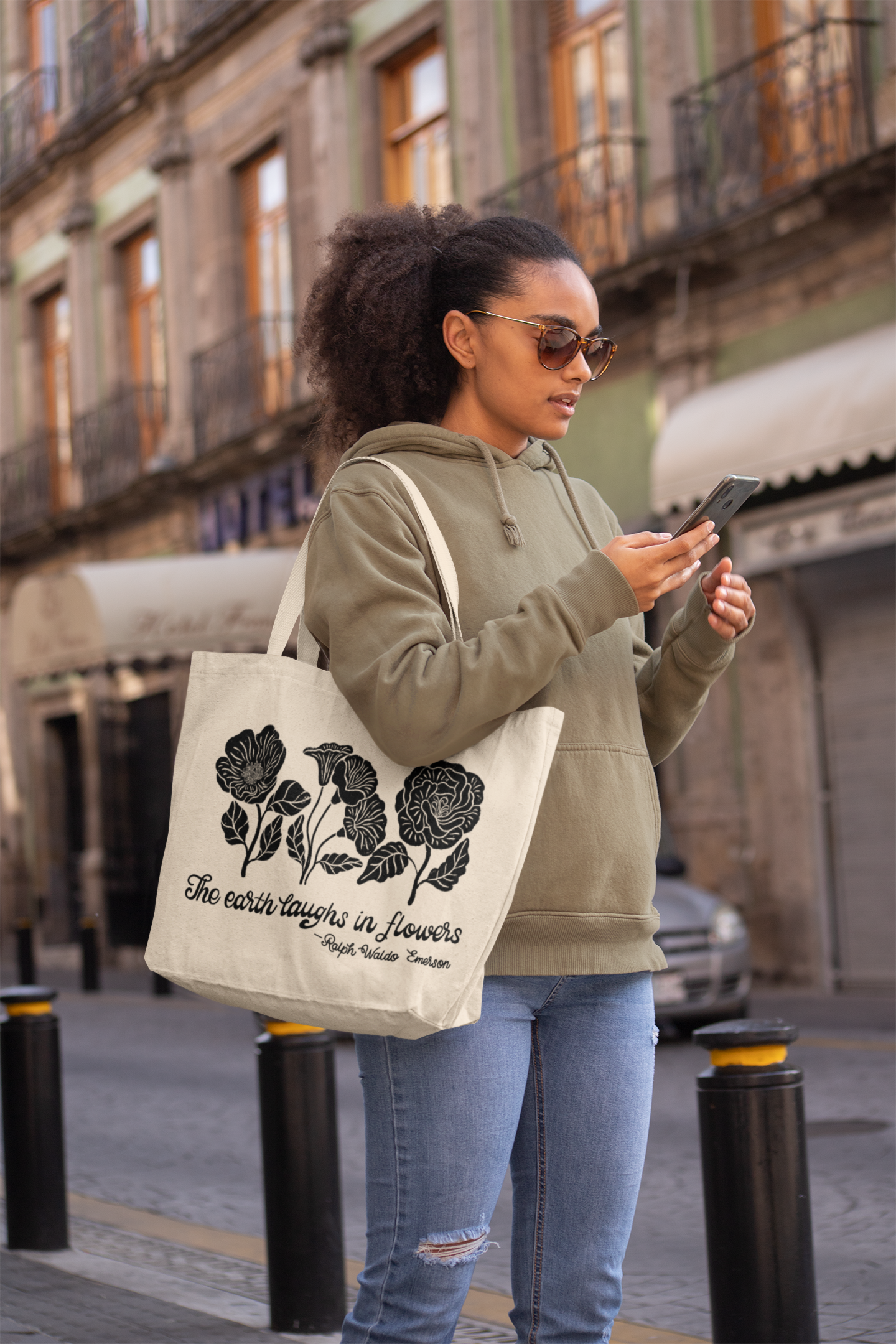 A woman on the phone carrying a canvas tote bag with black screen-printed moths and butterflies artwork